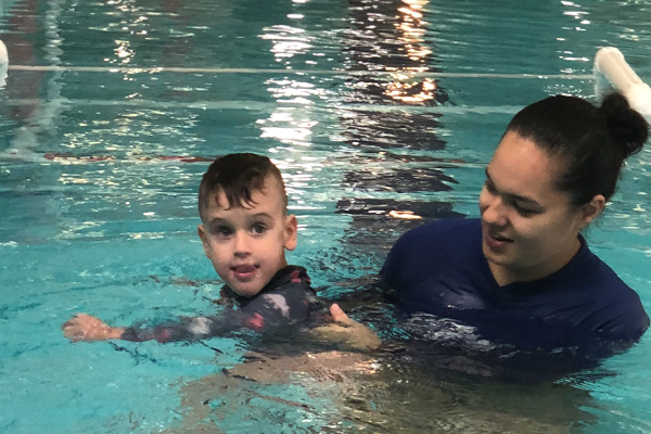 An infant boy submerged underwater with the guidance of an instructor